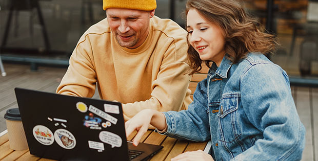 Eine junge Frau und ein junger Mann arbeiten zusammen am Laptop